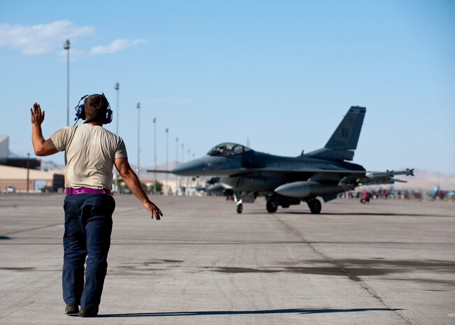 U.S. Air Force Senior Airman Joseph Archuleta, a crew chief assigned to the 510th Aircraft Maintenance Squadron, Aviano Air Base, Italy, directs an F-16 Fighting Falcon from the 31st Fighter Wing, Aviano AB, during Green Flag West 14-8, June 26, 2014, at Nellis Air Force Base, Nev. Green Flag West provides air and ground crews the opportunity to hone their skills and gain efficiency for future real-world operations. (U.S. Air Force photo by Airman 1st Class Thomas Spangler)