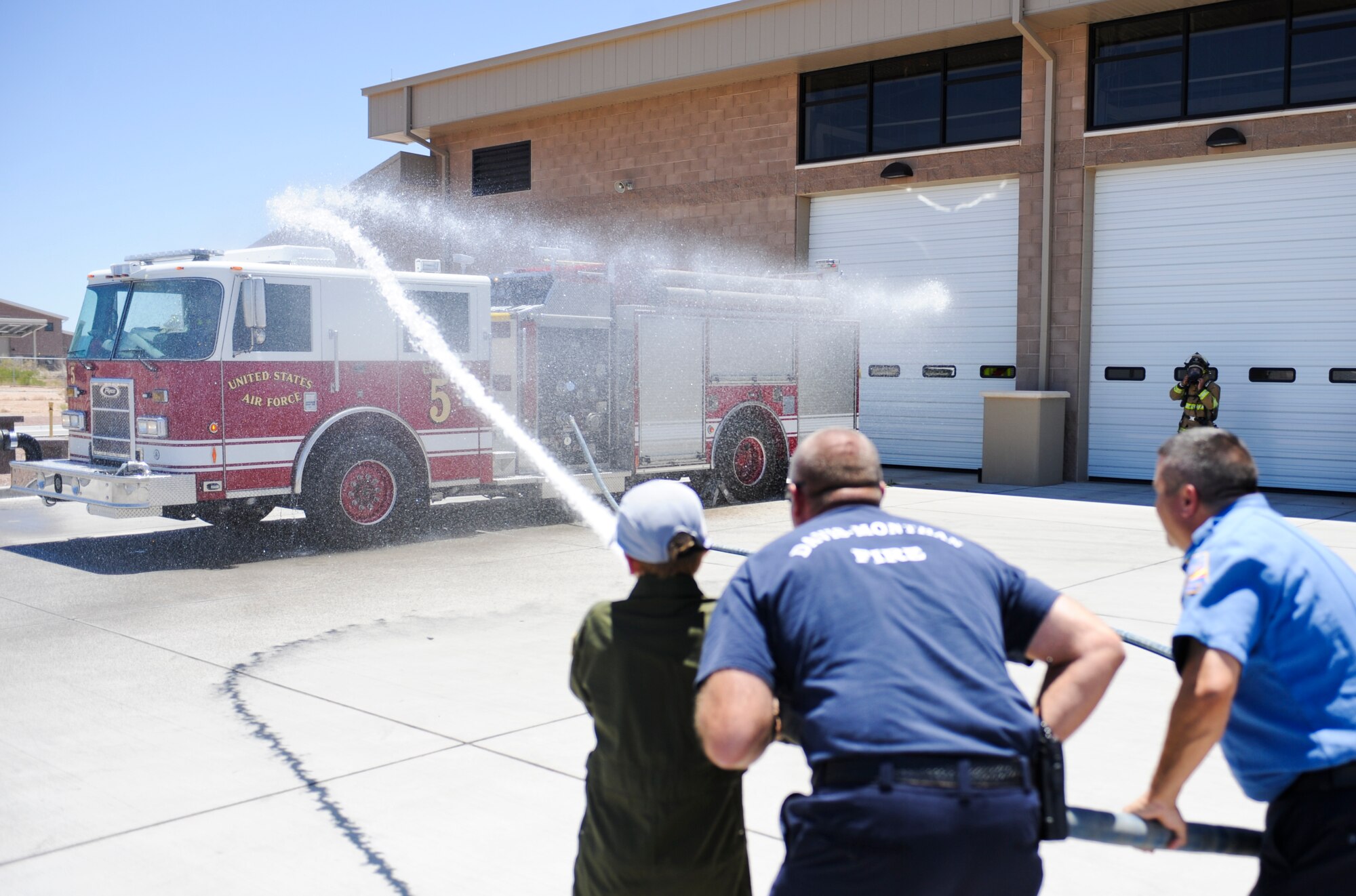 D-M firefighters help Trevor Pahl, 10, spray a fire truck during a Pilot for a Day event at Davis-Monthan Air Force Base, Ariz., June 27, 2014. D-M has been supporting the Pilot for a Day program, which was designed to focus on children who have serious or chronic health conditions, for more than 10 years. (U.S. Air Force photo by Airman 1st Class Sivan Veazie/Released)