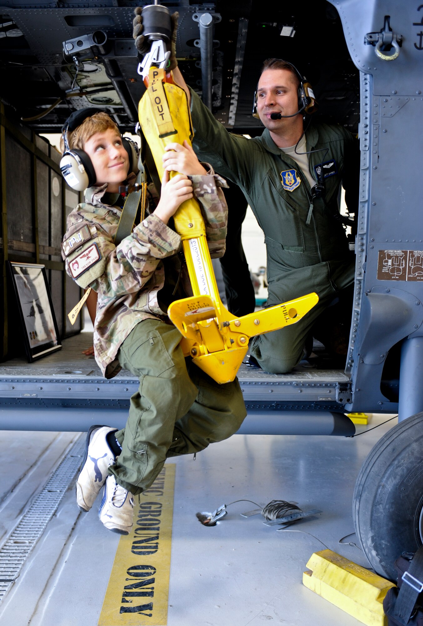 U.S. Air Force Senior Airmen Scott Garner, 305th Rescue Squadron aerial gunner, hoists Trevor Pahl, 10, up on an HH-60G Pavehawk during a Pilot for a Day event at Davis-Monthan Air Force Base, Ariz., June 27, 2014. During his visit to D-M, Pahl received various patches, souvenirs and coins to help him remember his unique tour. (U.S. Air Force photo by Airman 1st Class Sivan Veazie/Released)