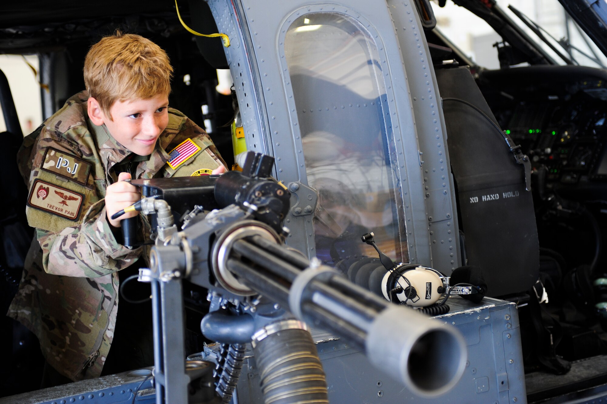 Trevor Pahl, 10, pretends to shoot an HH-60G Pavehawk mini-gun during a Pilot for a Day event at Davis-Monthan Air Force Base, Ariz., June 27, 2014. Pahl visited the rescue squadrons, the fire department and was able to fly the C-130 flight simulator. (U.S. Air Force photo by Airman 1st Class Sivan Veazie/Released)