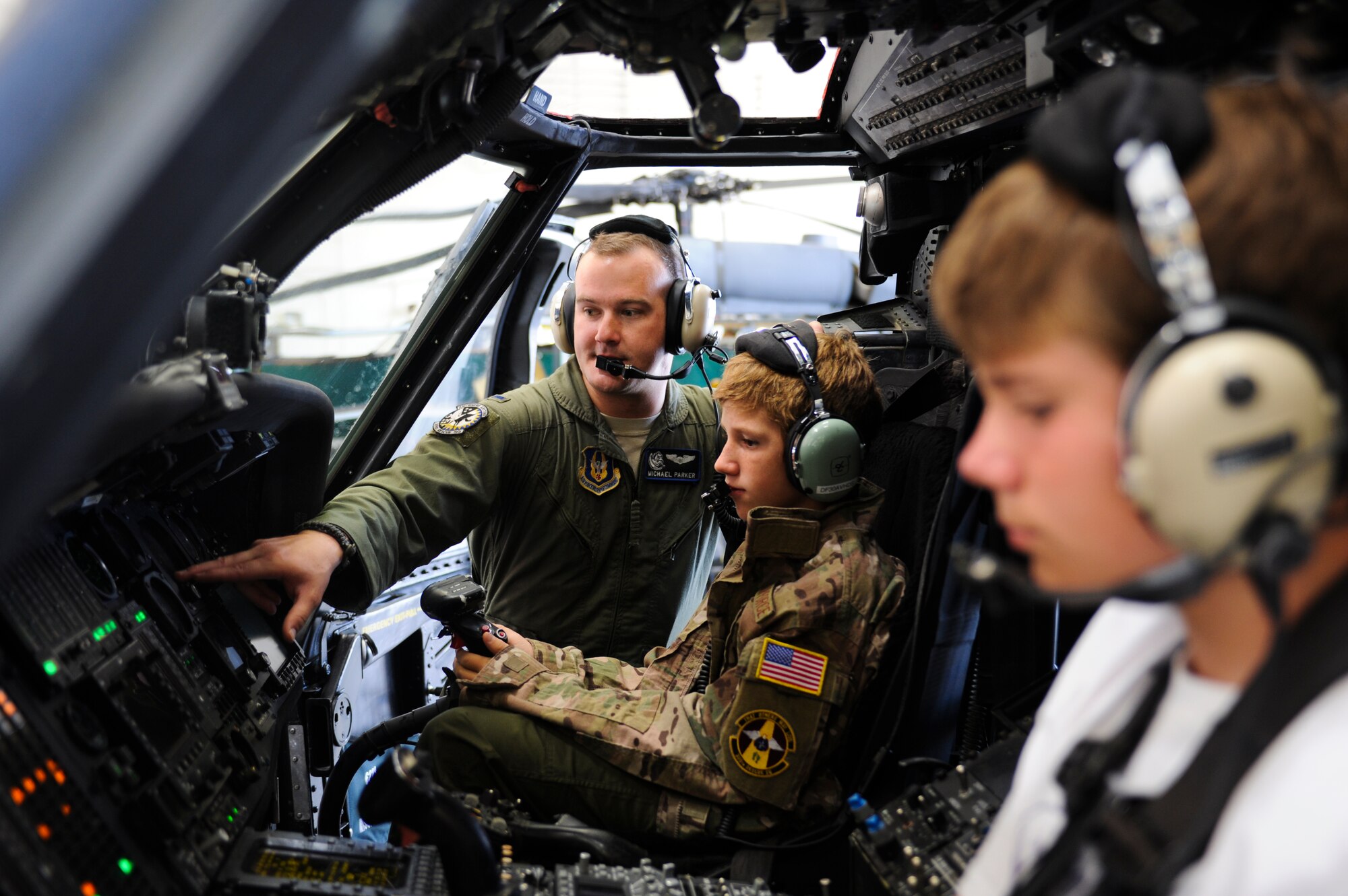 U.S. Air Force 1st Lt. Mike Parker, 305th Rescue Squadron HH-60G Pavehawk pilot, teaches Trevor Pahl, 10, the different functions of a helicopter while his brother Braeden Pahl, 13, sits next to him during a Pilot for a Day event at Davis-Monthan Air Force Base, Ariz., June 27, 2014. For Pahl, who had a severe traumatic brain injury over a year ago, the Pilot for a Day program was a significant milestone in his recovery. (U.S. Air Force photo by Airman 1st Class Sivan Veazie/Released)
