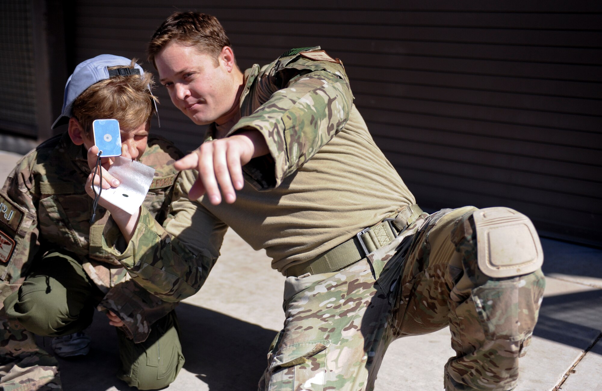 U.S. Air Force Tech. Sgt. Mark Quinn, 306th Rescue Squadron survival, evasion, resistance and escape craftsman, teaches Trevor Pahl, honorary Pilot for a Day, how to use a signal mirror at Davis-Monthan Air Force Base, Ariz., June 27, 2014. Pilot for a day is a program that strives to give each child a special day as an honorary pilot and a break from the challenges they face medically. This is month’s pilot for a day was selected by the Tucson Medical Center. (U.S. Air Force photo by Airman 1st Class Sivan Veazie/Released)