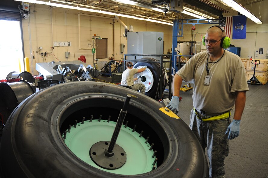 Tech. Sgt. Nathan Ennis, 2nd Maintenance Squadron wheel and tire NCO in-charge lowers a tire onto the one-man build up machine at Barksdale Air Force Base, La., June 23, 2014. During a recent competition the one-man build up machine completed assembly of three tires before the two-man team built one. (U.S. Air Force photo/Staff Sgt. Jason McCasland)