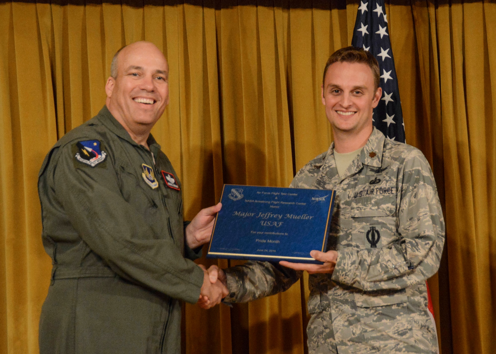 Brig. Gen. Michael Brewer (left), 412th Test Wing commander, presents Maj. Jeffrey Mueller with a plaque from the 412th Test Wing and NASA Armstrong Flight Research Center for his contributions to the LGBT Pride Month luncheon June 26. (U.S. Air Force photo by Rebecca Amber)