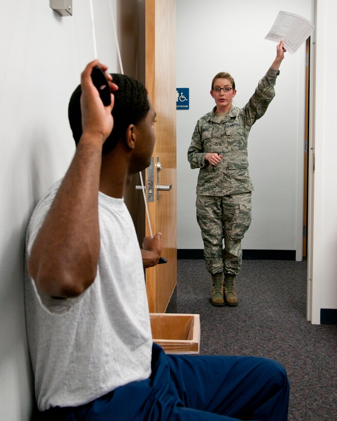 Airman 1st Class Felicia Grassel, 90th Medical Operations Squadron physical therapy technician, explains the proper way to perform a physical therapy exercise to Tech. Sgt. Markeus Lee, 90th Maintenance Operations Squadron Facility Maintenance Training Section NCO-in-charge, June 25, 2014, in the Freedom Hall Fitness Center. (U.S. Air Force photo by Airman 1st Class Jason Wiese)
