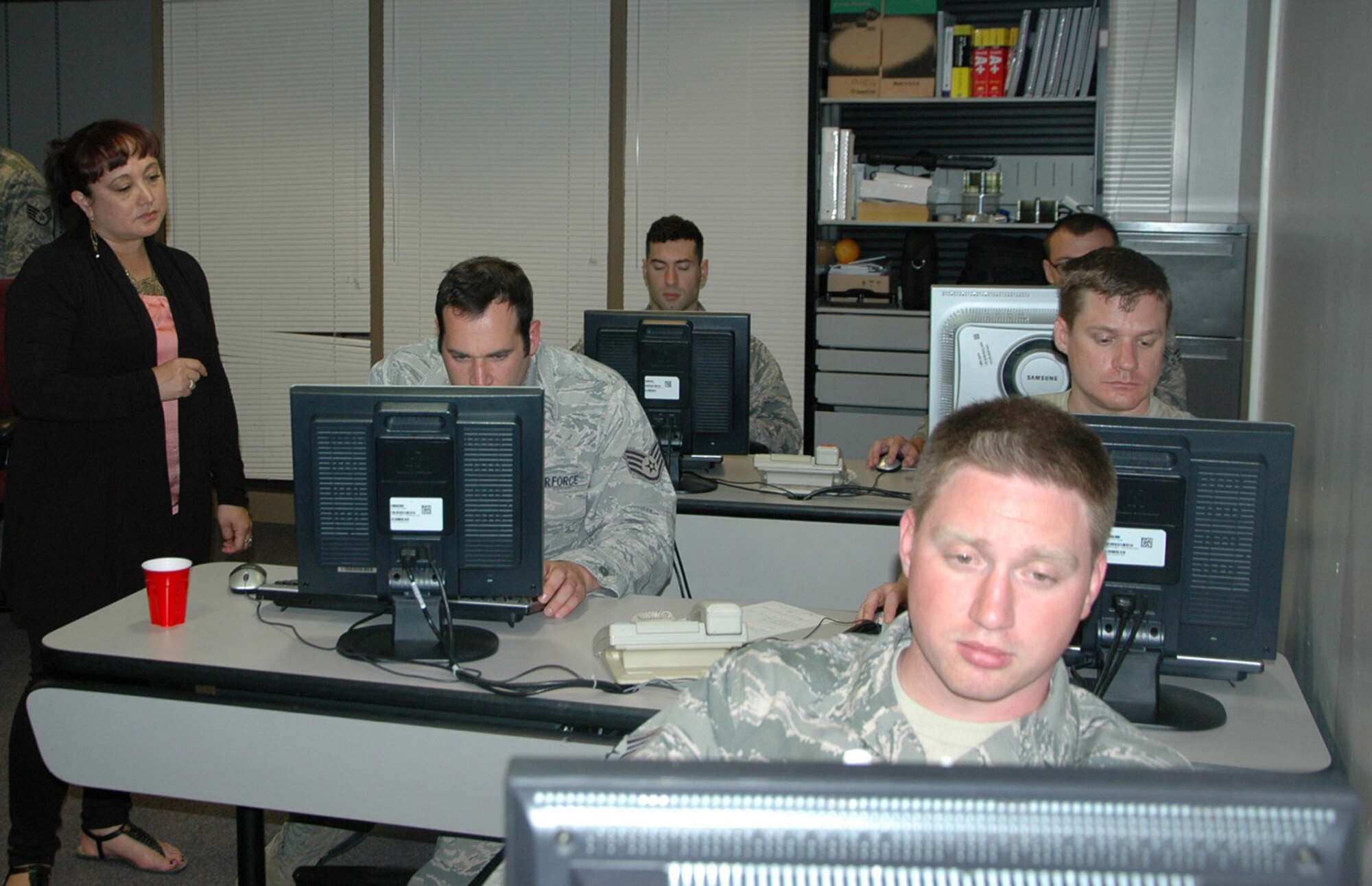 Master Sgt. Diana Feeley, 446th Airlift Wing network operations (left), watches one of the Airmen from the 23rd Combat Communications Squadron, Travis Air Force Base, California tackle a computer issue.  The Reservists from Travis AFB, and one from Niagara Falls, New York, were at Joint Base Lewis-McChord, Washington in June to help the active-duty 627th Communications Squadron here prepare for a Command Cyber Readiness Inspection.  (U.S. Air Force Reserve photo by Sandra Pishner)
