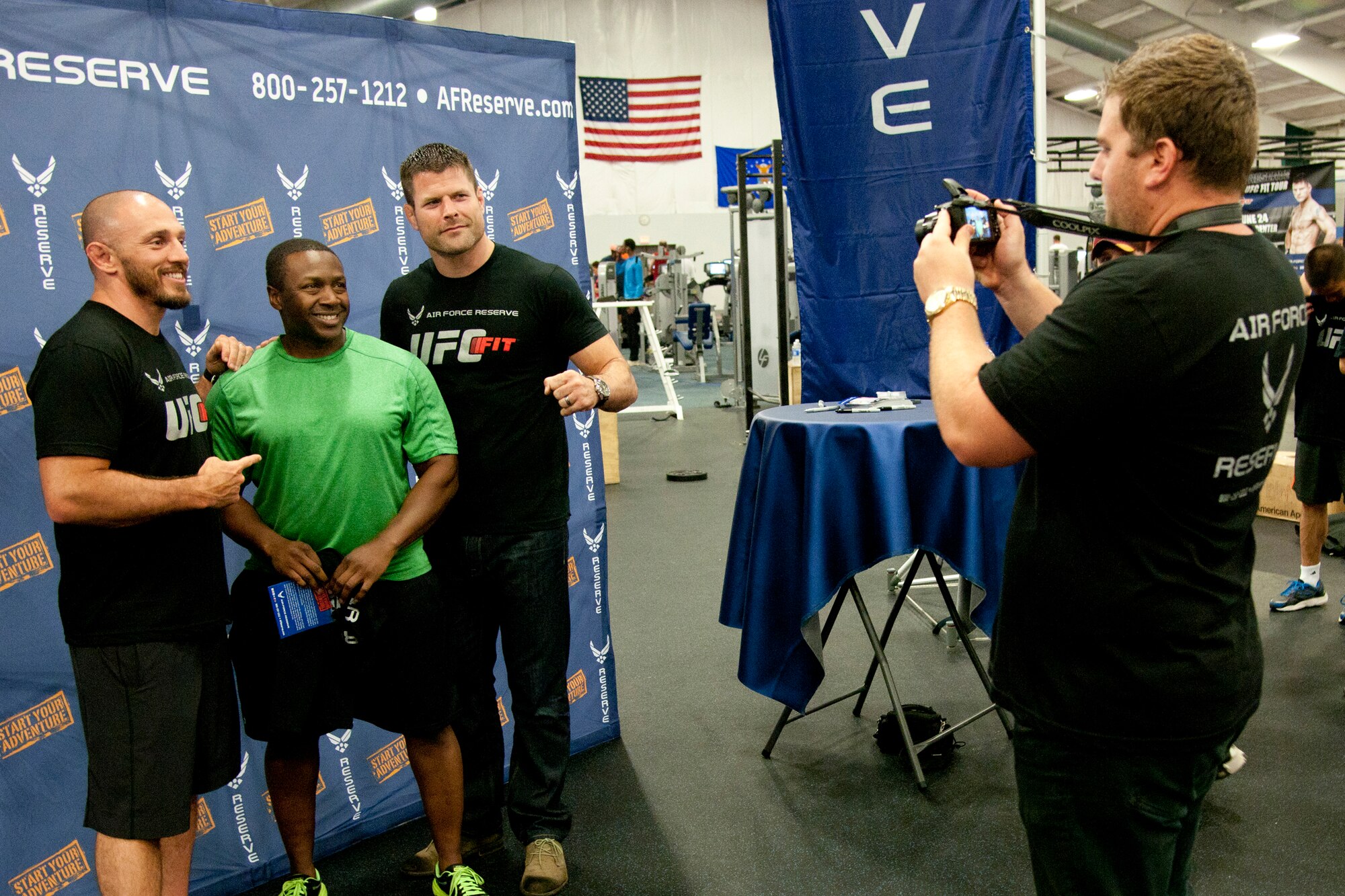 Mike Dolce, an Ultimate Fighting Championship FIT coach, and Brian Stann, a UFC fighter, veteran and Silver Star recipient, pose for photos with a fan at the Andrews Fitness Center on June 24, 2014. The UFC FIT program taught attendees about achieving maximum physical fitness through living a healthy lifestyle, and was sponsored by the Air Force Reserve. (U.S. Air Force photo/Airman 1st Class J.D. Maidens) 