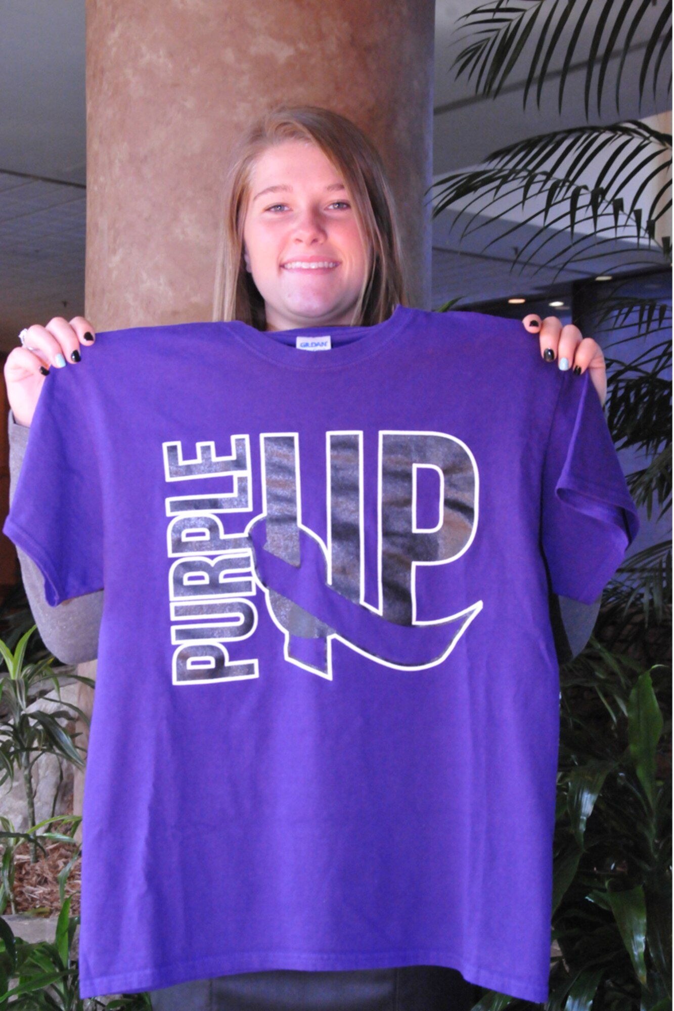 McKenna Deckard, Air Force Reserve Teen Leadership Council member, displays a Purple Up! t-shirt she designed for a reserve youth project at Yellow Ribbon in Atlanta, Ga. June 27 to 29, 2014. Two council members attended the event to identify issues that affect Air Force Reserve youth and develop effective strategies to address them. The Yellow Ribbon Program promotes the well-being of reservists and their families by connecting them with resources before and after deployments. (U.S. Air Force photo/Staff Sgt. Terrica Jones)