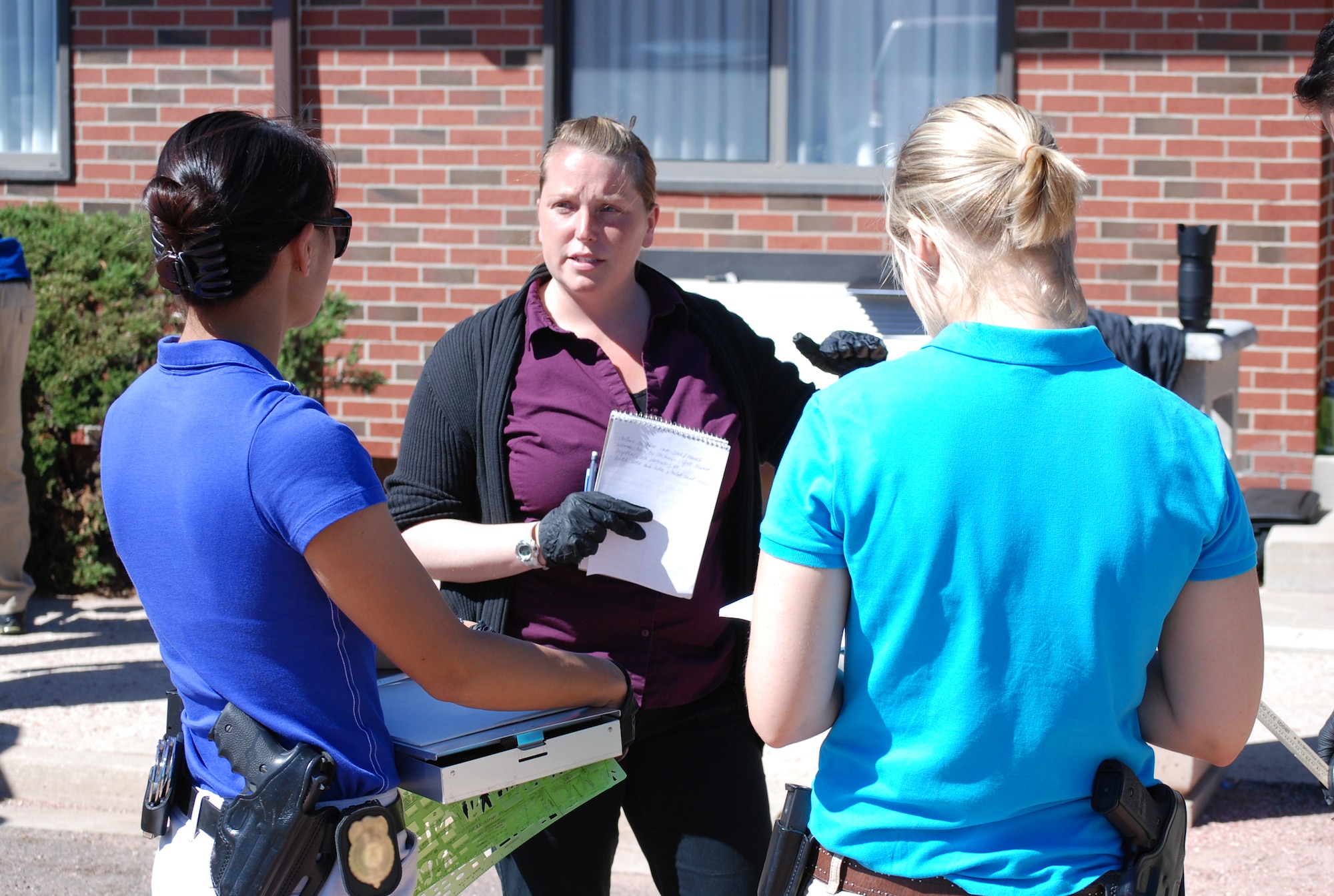 PETERSON AIR FORCE BASE, Colo. — Special agents with the Air Force Office of Special Investigations 8th Field Investigations Squadron at Peterson discuss tasks, responsibilities and how they are going to go about investigating a simulated crime scene at a hotel which involved a deceased victim June 18 here. (U.S. Air Force photo/Michael Golembesky)