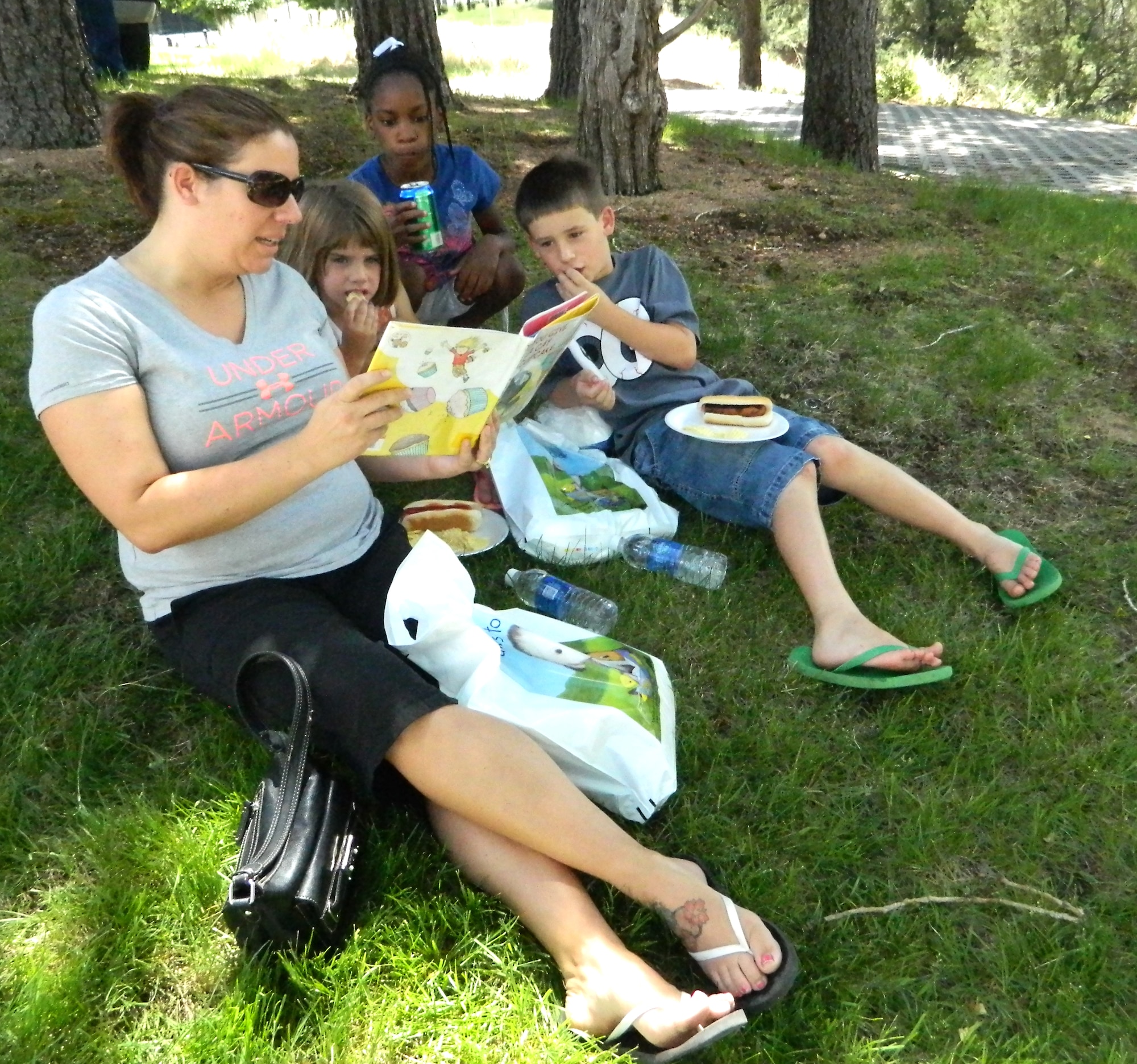 Nicole Brown reads "If You Can GIve a Cat a Cupcake" to her children and their friend for the Paws to Read Program. This is the first year her children have participated in the Academy's Summer Reading Program. There are Paws to Read events scheduled through Aug. 9. Check with the Academy Library for more information. (U.S. Air Force photo/Amber Baillie)