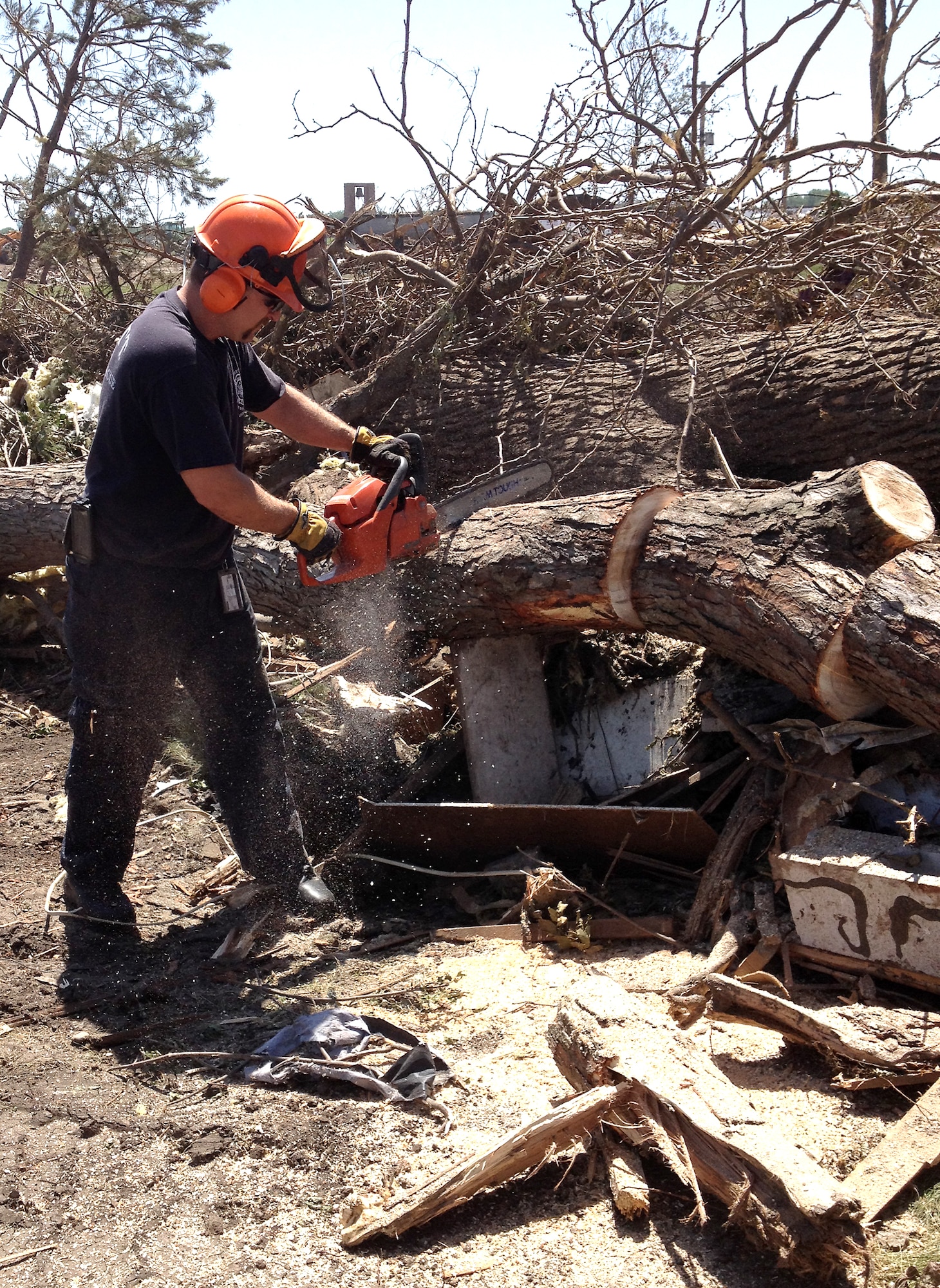 Matt Croteau, a firefighter from the 55th Civil Engineering Squadron at Offutt Air Force Base, Nebraska, cuts debris in Pilger, Nebraska, June 20 with a chain saw. Croteau was part of a group of volunteers from Offutt who helped with the cleanup efforts in Pilger following a tornado that destroyed approximately 75 percent of the town June 16. (Courtesy photo)