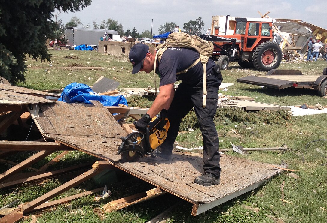 Ron Dawson, a firefighter from the 55th Civil Engineering Squadron at Offutt Air Force Base, Nebraska, cuts debris in Pilger, Nebraska, June 18 with a K-12 saw. Croteau was part of a group of volunteers from Offutt who helped with the cleanup efforts in Pilger following a tornado that destroyed approximately 75 percent of the town, June 16. (Courtesy photo)