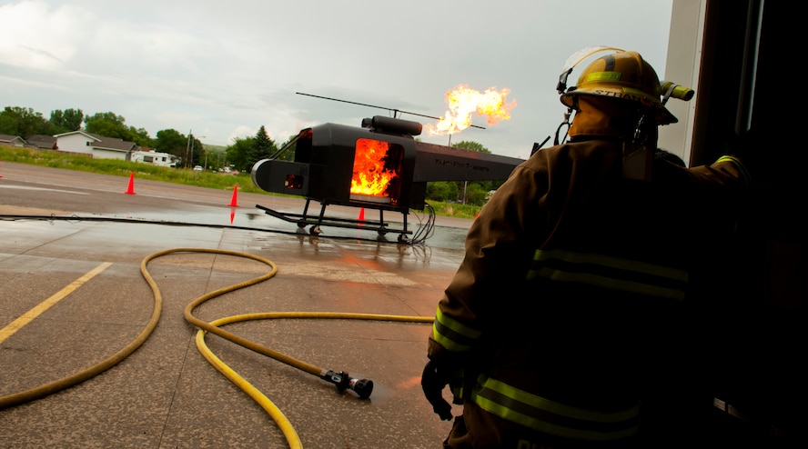 A firefighter watches as the helicopter trainer burns during a live fire training exercise in Burlington, N.D., June 23, 2014. Members of the Minot Air Force Base fire department trained Burlington volunteer firemen. (U.S. Air Force photo/Senior Airman Brittany Y. Bateman)