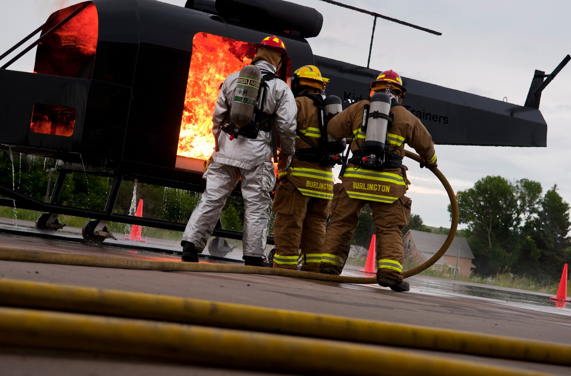 Staff Sgt. Luke Kroeplin, 5th Civil Engineer Squadron firefighter, shows members of the Burlington Fire Department the proper way of putting out a fire in Burlington, N.D., June 23, 2014. Burlington Fire Department is based solely on volunteerism, and they respond to 50-70 calls per year, ranging from wild land to structure fires.  (U.S. Air Force photo/Senior Airman Brittany Y. Bateman)