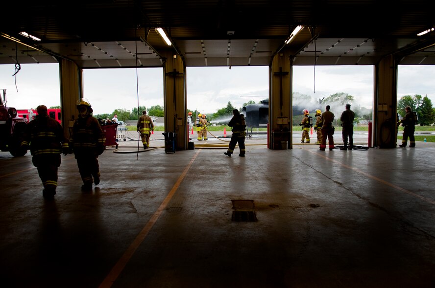 Members of the Burlington Fire Department watch as their fellow firemen put out a fire during training with Minot Air Force Base Fire Department in Burlington, N.D., June 23, 2014. Burlington Fire Department is based solely on volunteerism, and they respond to 50-70 calls per year, ranging from wild land to structure fires.  (U.S. Air Force photo/Senior Airman Brittany Y. Bateman)