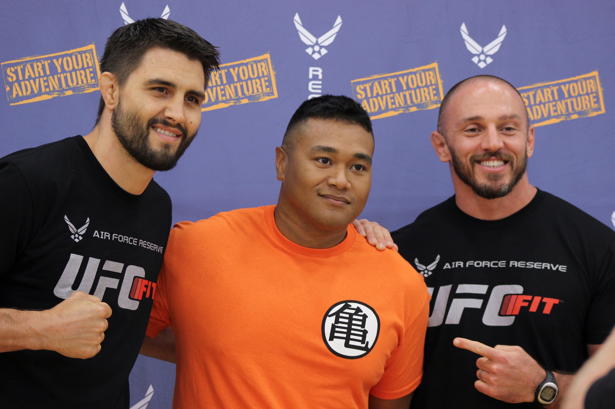 Senior Airman Joseph McGhee, 436th Comptroller Squadron financial service technician, center, poses for a photo with Carlos Condit, Ultimate Fighting Championship fighter, left, and Mike Dolce, UFC coach, June 26, 2014, at the fitness center on Dover Air Force Base, Del. Condit and Dolce met with Airmen during a meet-and-greet that took place after the workshop. (U.S. Air Force photo/Herbert E. Welday III) 