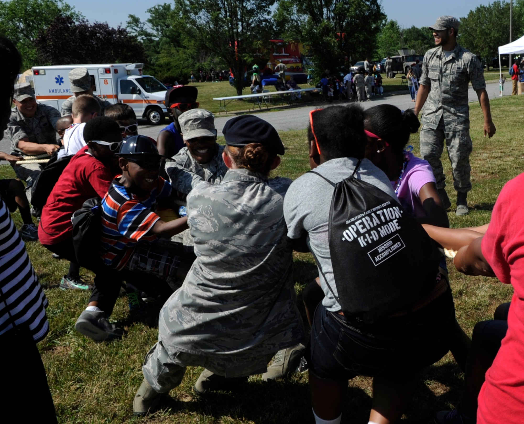 Operation KID Mode participants and volunteers play tug-of-war on Joint Base Andrews, Md., June 27, 2014. More than 70 military personnel volunteered to run this kid-friendly, mock deployment in-processing experience.  OKM featured things such as weapons demo, kid-friendly physical fitness, a bounce house and an explosive ordnance disposal demo.  (U.S Air Force photo/Senior Airman Nesha Humes)