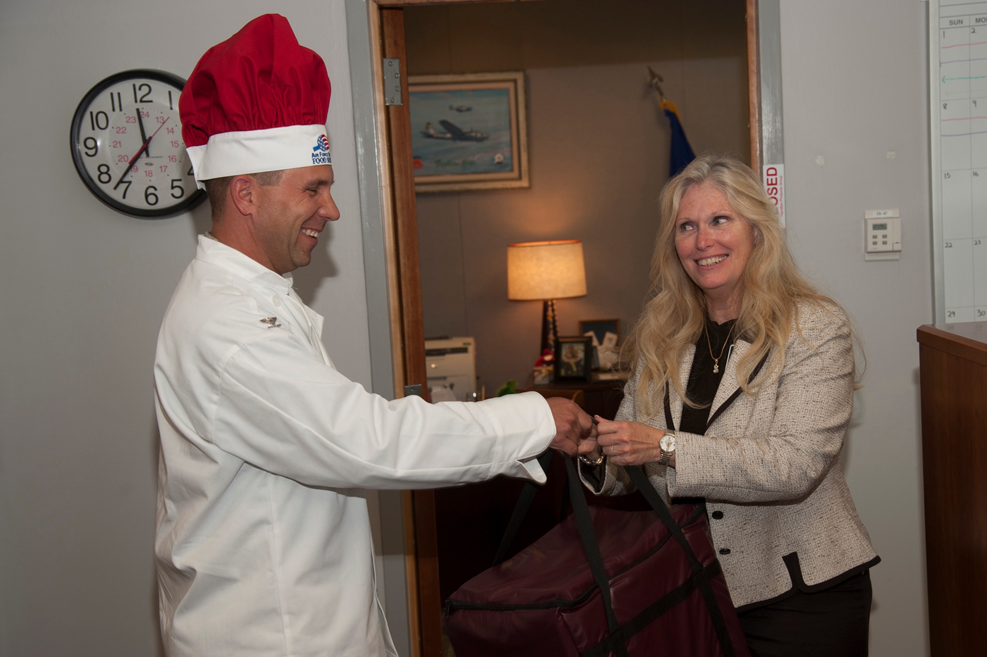PETERSON AIR FORCE BASE, Colo. -- Col. John Shaw, 21st Space Wing commander, delivers pizza June 26 to Barbara Westgate, Air Force Space Command executive director. The special delivery was made to announce the start of a new dining option – the Colorado Pizza Company. Located in The Club, the Colorado Pizza Company offers a variety of Colorado-themed specialty pies for eat-in or carry out. Hours are Monday 3 p.m.-8 p.m. and Tuesday- Friday 11 a.m.-8 p.m. For information or to place an order, call 574-8863. (U.S. Air Force photo/Robb Lingley)