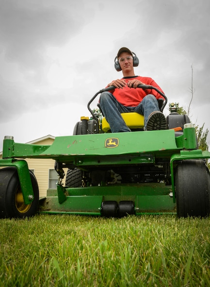 Douglas Dicken, a contractor working for Balfour Beatty Communities, mows the lawn near a residence in housing on Minot Air Force Base, N.D., June 13, 2014. According to the BBC residents guide, residents in housing are responsible for watering the lawn trees and shrubs that surround their home as well as mowing their back yard, if they have a fence, and trimming their fence lines. Those who do not own lawn care equipment are able to check it out from the self help building near the Airman and Family Readiness Center at 289 Peackeeper.  (U.S. Air force photo/Senior Airman Stephanie Morris)