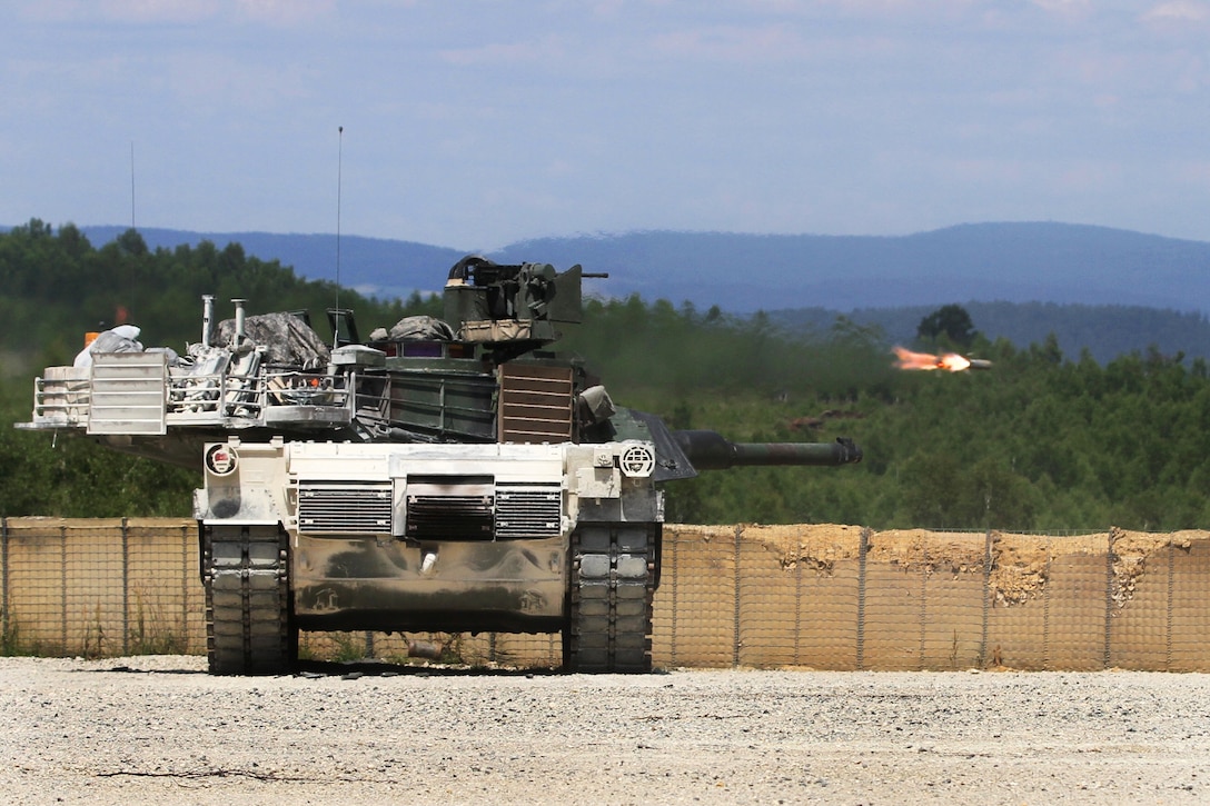 A U.S. Army M1A1 Abrams tank engages targets as a tube-launched, optically-tracked, wire-guided missile system fired from a M2 Bradley fighting vehicle flies by during a combined-arms, live-fire exercise at the Joint Multinational Readiness Center in Hohenfels, Germany, June 26, 2014.