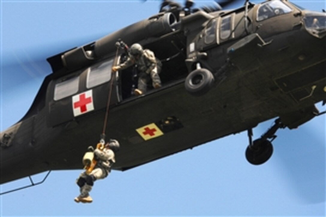 Army Sgt. Michael Severin guides the hoist from inside a UH-60 Black Hawk helicopter to bring up Army Sgt. 1st Class Greg Holland during the fourth annual Great Plains Zone Interagency Helicopter Medevac training near Pactola Reservoir, S.D., June 25, 2014. Severin is assigned to the South Dakota Army National Guard's Company C, 1st Battalion, 189th Aviation Regiment, and Holland is assigned to the Company D, 1st Battalion, 112th Aviation Regiment.