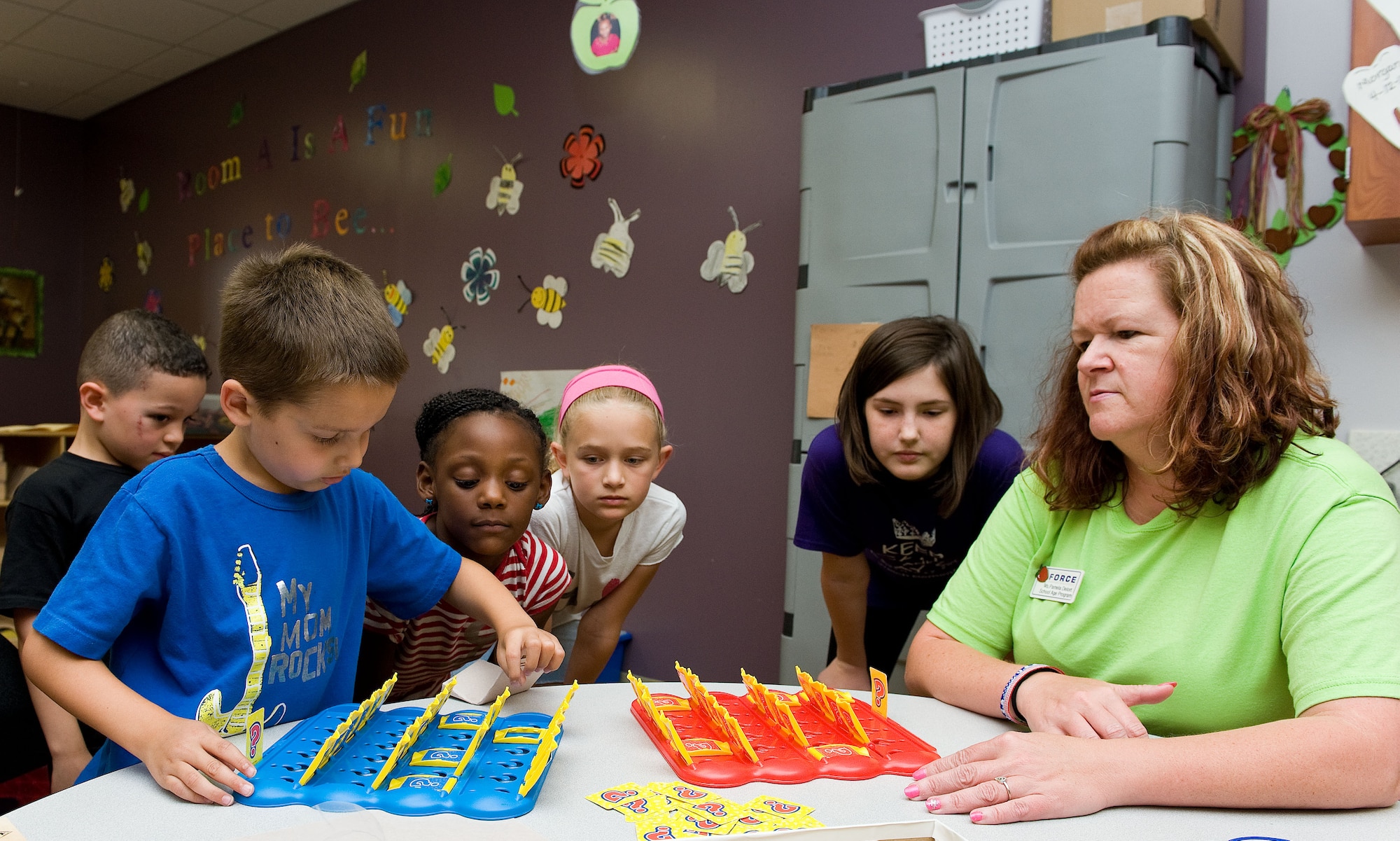 Jacob Franko, left, son of Staff Sgt. Peter Franko, 9th Airlift Squadron, and Pam Delort, right, 436th Force Support Squadron Youth Center school age program assistant, play ?Guess Who,? June 27, 2014, at the Youth Center on Dover Air Force Base, Del. Children are able to move around to different activity rooms that interest them. (U.S. Air Force photo/Roland Balik)