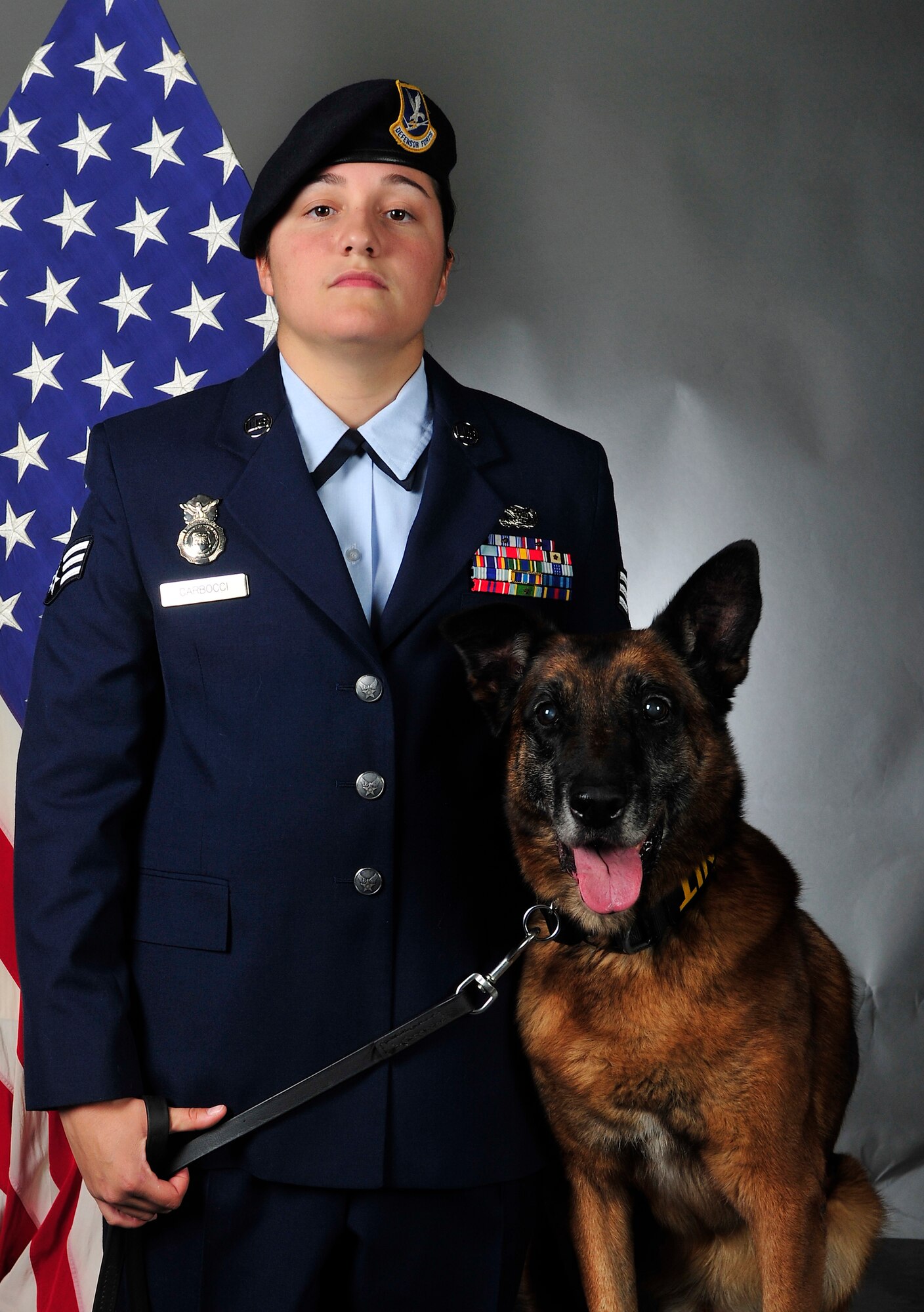 Staff Sgt. Tatiana Carbocci, 8th Security Forces Squadron military working dog handler, poses alongside military working dog Rico for an official photo at Kunsan Air Base, Republic of Korea, Oct. 22, 2013. For more than nine years, Rico served the Wolf Pack as an explosive detection dog, ensuring the security of Kunsan. (U.S. Air Force photo by Senior Airman Clayton Lenhardt/Released)