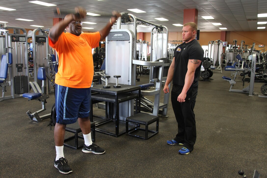Retired Army Sgt. 1st Class Jimmy Tootle completes a front raise with a 15-pound bar during a circuit training session with Marine Corps Air Station Cherry Point's Marine Corps Community Services Semper Fit personal trainer Jason B. Garris at the Devil Dog Gym Feb. 19, 2014. 