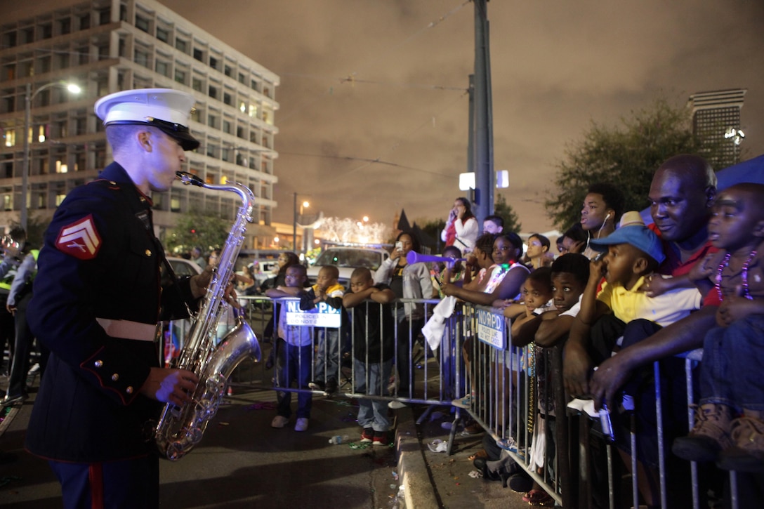 Cpl. Robert Flack, a saxophone player in the brass section of Marine Corps Band New Orleans, entertains the crowd during a long break in the Krewe of Bacchus parade here, March 2, 2014. Marine Corps Band New Orleans performed during the parade Sunday evening bringing many cheers from the lively and supportive parade attendees. (Marine Corps photo by Lance Cpl. Brytani Musick)