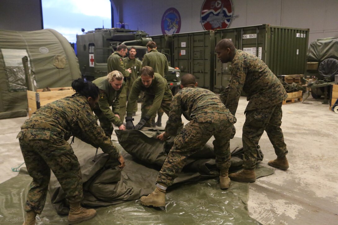 Medical personnel with 2nd Supply Battalion, Combat Logistics Regiment 25, 2nd Marine Logistics Group and Joint Medical Task Force, Host Nation Support Battalion unfold an inflatable stationary aid station at Vaernes Garrison, Norway, Feb. 28, 2014. The teamwork brought U.S. Navy corpsmen and Norwegian medical staff together and gave the corpsmen a look at Norwegian equipment they might work with during Cold Response 2014. 