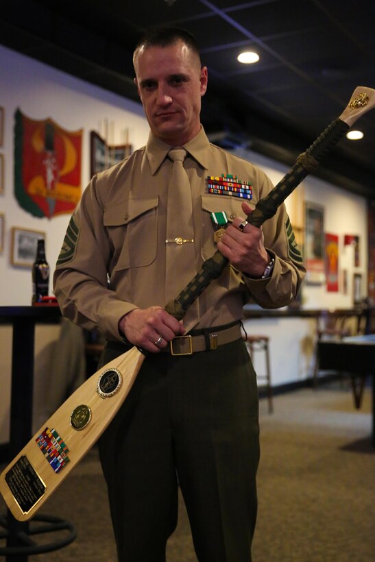 Gunnery Sgt. Joshua W. Raposa, the company gunnery sergeant for Headquarters and Support Battalion, 2nd Battalion, 2nd Marine Regiment, 2nd Marine Division, poses with a paddle he was awarded at his retirement ceremony, aboard Marine Corps Base Camp Lejeune, Feb. 6, 2014. Raposa is retiring after 20 years of faithful service to the Marine Corps. The paddle represents a token of appreciation for the dedication and service to the unit.