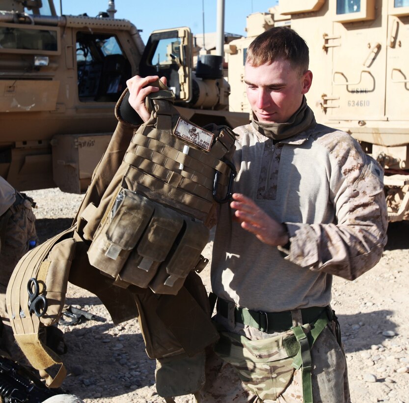 Corporal Anthony Cubbage, an infantry Marine with 3rd Platoon, Charlie Company, 1st Battalion, 9th Marine Regiment, dons his protective vest during a gear inspection aboard Patrol Base Boldak in Helmand province, Afghanistan, Feb. 21, 2014. Gear inspections are critical before each patrol to ensure maximum safety and reliability in each team. (U.S. Marine Corps photo by Cpl. Cody Haas/ Released)