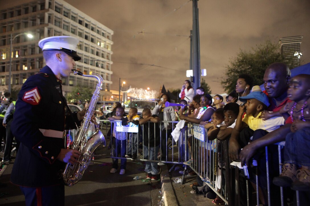 Cpl. Robert Flack, a saxophone player in the brass section of Marine Corps Band New Orleans, entertains the crowd during a long break in the Krewe of Bacchus parade here, March 2, 2014. Marine Corps Band New Orleans performed during the parade Sunday evening bringing many cheers from the lively and supportive parade attendees. (Marine Corps photo by Lance Cpl. Brytani Musick)