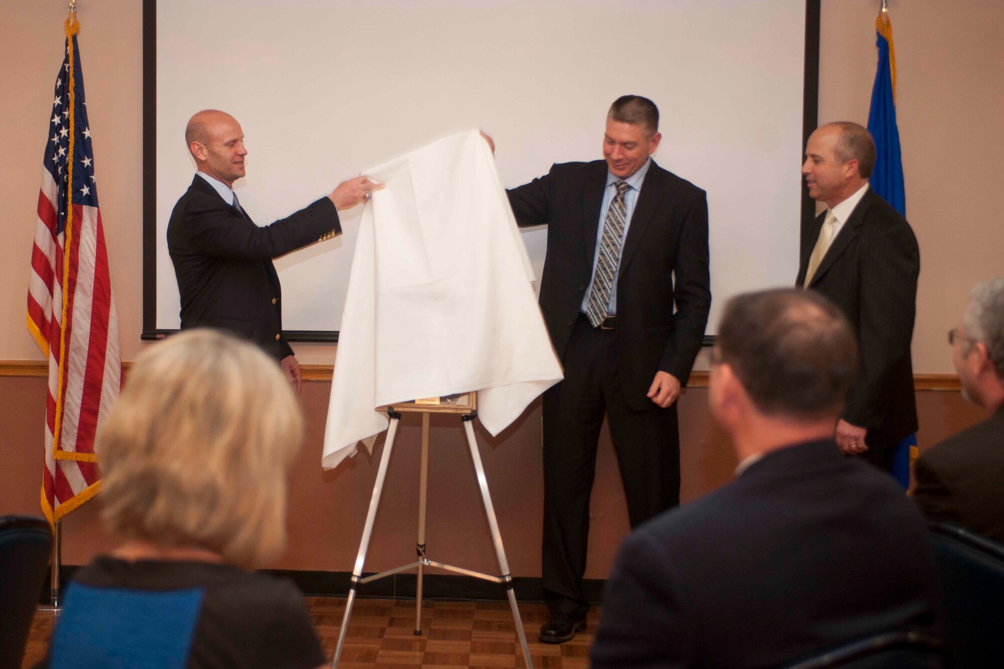 ALTUS AIR FORCE BASE, Okla. – Col. Anthony Krawietz, former Altus AFB wing commander, and Col. Bill Spangenthal, 97th Air Mobility Wing commander, unveil a portrait of Mr. Jeff Greenlee, President of NBC Bank in Altus, who was named a “Friend of Altus” at an induction ceremony held at Club Altus Feb. 28, 2014. The ceremony consisted of a reception, dinner and an unveiling of portraits that will join the portraits of other Friends of Altus in the Wing headquarters building. The ceremony brings the total number of individuals who have been named a Friend of Altus to 20. (U.S. Air Force photo by Senior Airman Jesse Lopez/Released)