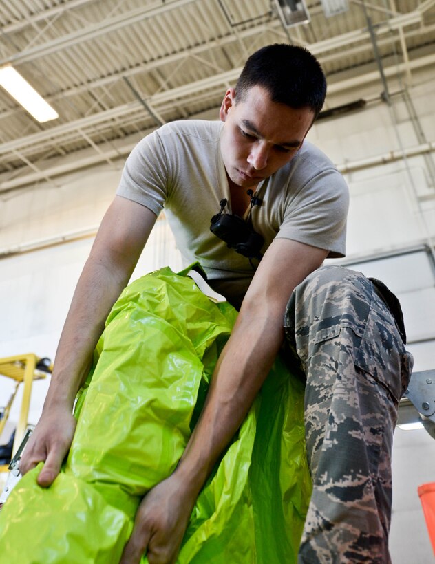 Senior Airman Matthew Hung, 28th Civil Engineer Squadron emergency management technician, dons protective gear during a training exercise at Ellsworth Air Force Base, S.D., Jan. 23, 2014.  Participants in the exercise wore Level A hazardous material suits to protect themselves while attempting to control and identify a simulated unknown substance. (U.S. Air Force photo by Senior Airman Zachary Hada/Released)