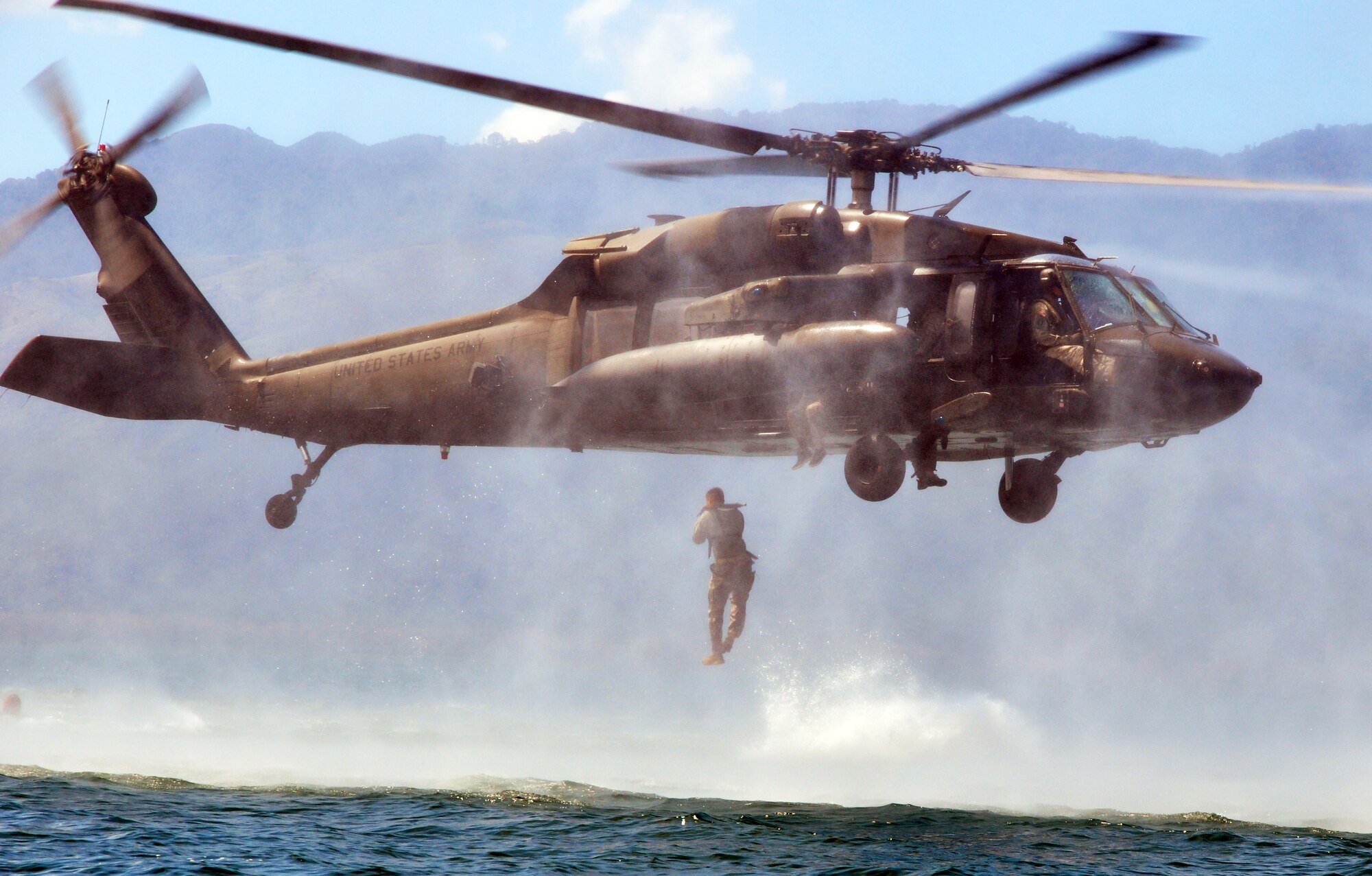 A member of Joint Task Force-Bravo jumps from a UH-60 Blackhawk helicopter during helocast training at Lake Yojoa, Honduras, Feb. 25, 2014. Several members of the Task Force spent the day training on helocasting, caving ladder, and overwater hoist operations. (U.S. Air Force photo by Capt. Zach Anderson)