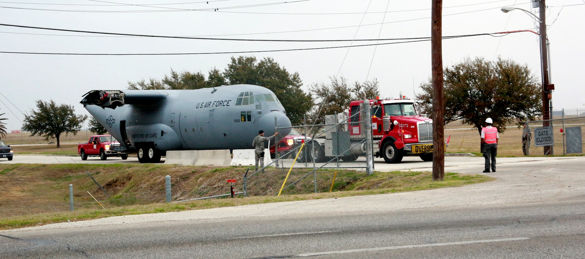 Joint Base San Antonio-Lackland 802nd Security Forces Squadron members open the Military Highway Gate Sunday during the relocation of a retired and partially disassembled Air Force C-130 Hercules cargo aircraft. The C-130 moved to JBSA-Camp Bullis and will be used by the 937th Training Group to provide realistic aeromedical evacuation training to more than 1,300 students annually. (U.S. Air Force photo by Dan Solis)