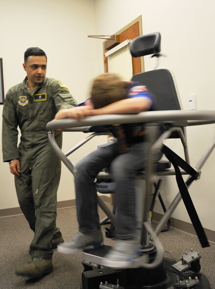 Tech. Sgt. Vikas Kumar, 92nd Aerospace Medicine Squadron aerospace and operational physiology NCO in charge, spins Gabe Naught, a Rosalia Boy Scout, on the Barany chair while his eyes and ears are covered during a base tour at Fairchild Air Force Base, Wash., Feb. 26, 2014. The Barany chair is a training tool that helps Airmen understand spatial disorientation and learn to trust their instruments. (U.S. Air Force photo by Airman 1st Class Janelle Patiño/ Released)
