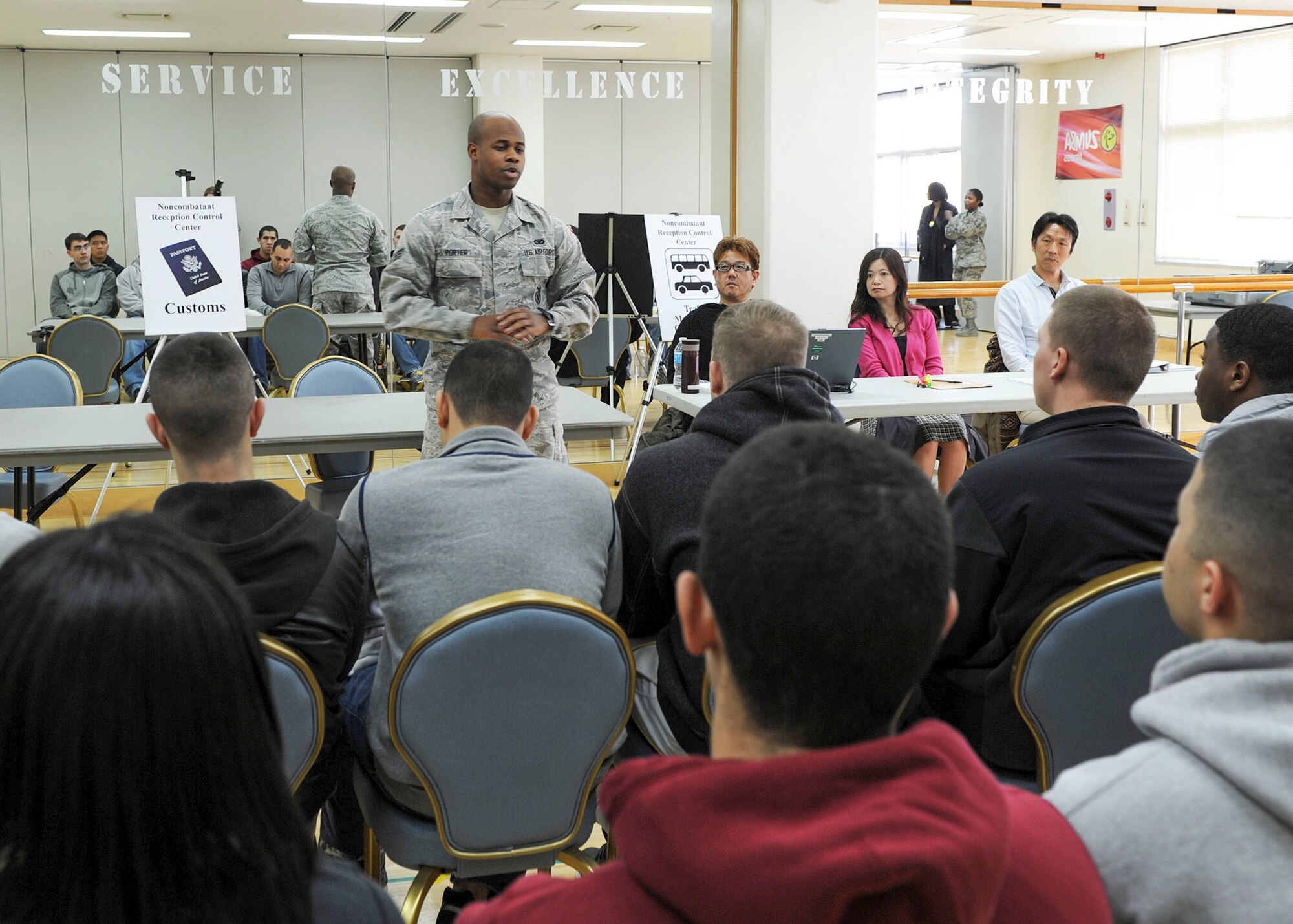 Senior Airman Alvin Porter, customsimmigration inspector with the 374th Force Support Squadron briefs simulated non-combatant evacuees during a Samurai Readiness Inspection Mar. 3, 2014, at the Taiyo Community Center at Yokota Air Base, Japan. As the mobility hub of the Western Pacific, Yokota may be called upon to support regional non-combatant evacuation operations in the event of a crisis. Inspections like this ensure the base’s readiness to carry out its mission. (U.S. Air Force photo by Senior Airman Desiree Economides/Released)   