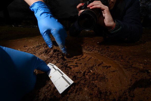 A photograph of a footprint being measured in the mud similar to the way an Air Force Office of Special Investigations criminal investigator would collect evidence. The U.S. Air Forces in Europe and Air Forces Africa OSI criminal investigators use many different detailed methods to collect evidence and intel to solve crimes and protect the members of the Kaiserslautern Military Community. (U.S. Air Force photo illustration/Airman Dymekre Allen)