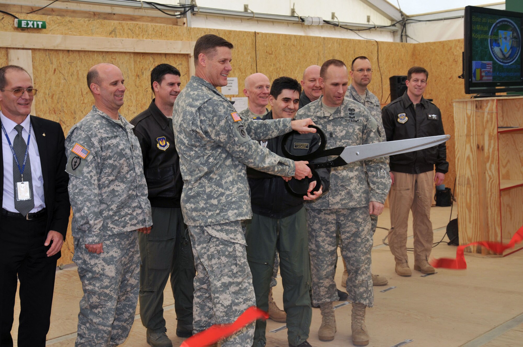 Maj. Gen. John R. O'Connor, the commanding general of the 21st Theater
Sustainment Command, and Air Force Maj. Gen. Laurian Anastasof, chief of the
Romanian Air Force Staff, use ceremonial scissors to cut the commemorative
ribbon as key allied organizational, base and facility leaders look on
during the ceremony conducted Feb. 28 at the MK Passenger Transit Center.  (U.S. Air Force photo/ Senior Master Sgt. Steve Horton)