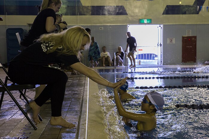 Lance Cpl. Nikolette Alexander high fives a Japanese swimmer at the end of her race at the IronWorks Gym indoor pool aboard Marine Corps Air Station Iwakuni, Japan, Feb. 23, 2014. According to Mitsuki Ikeda, head coach of Fitness Ocean swim team, events like these are necessary in continuing to build upon good relations between Americans and Japanese.