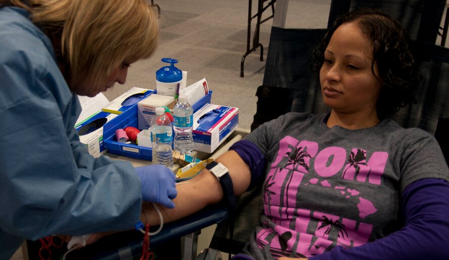 Senior Airman Leatha Brown, 90th Force Support Squadron missile chef, watches as Nancy Johnson, United Blood Services volunteer, prepares to draw blood from her arm. Johnson cleans each volunteers arm with rubbing alcohol before inserting the needle. (U.S. Air Force photo by Airman 1st Class Brandon Valle) 