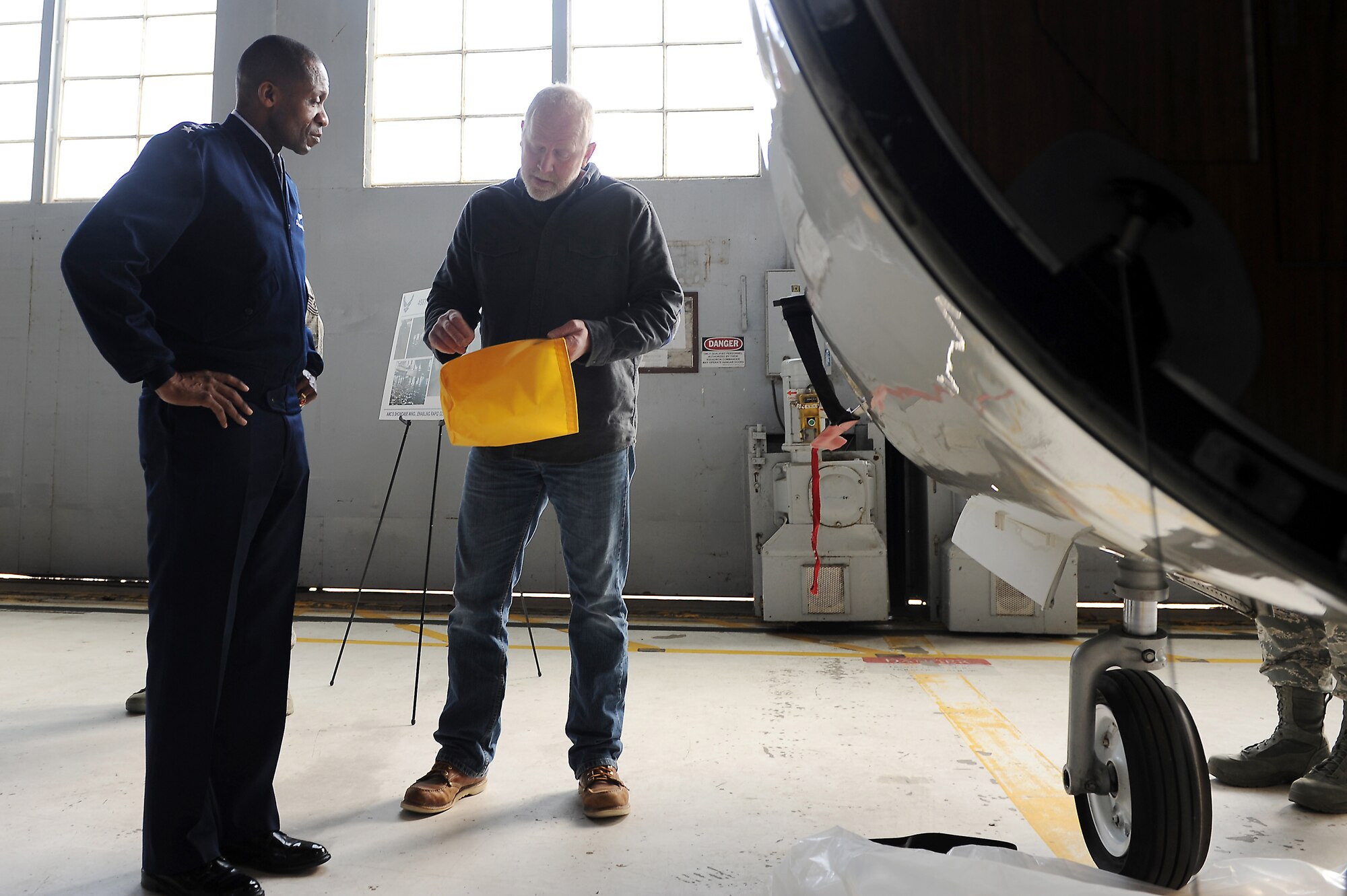 Lt. Gen. Darren W. McDew, 18th Air Force commander, receives a briefing from Jim Knake, 375th Operation Support Squadron, during an official visit here Feb. 28, 2014 at Scott Air Force Base, Ill. Knake briefed McDew on new equipment being used aboard the C-21. (U.S. Air Force photo/Senior Airman Divine Cox)