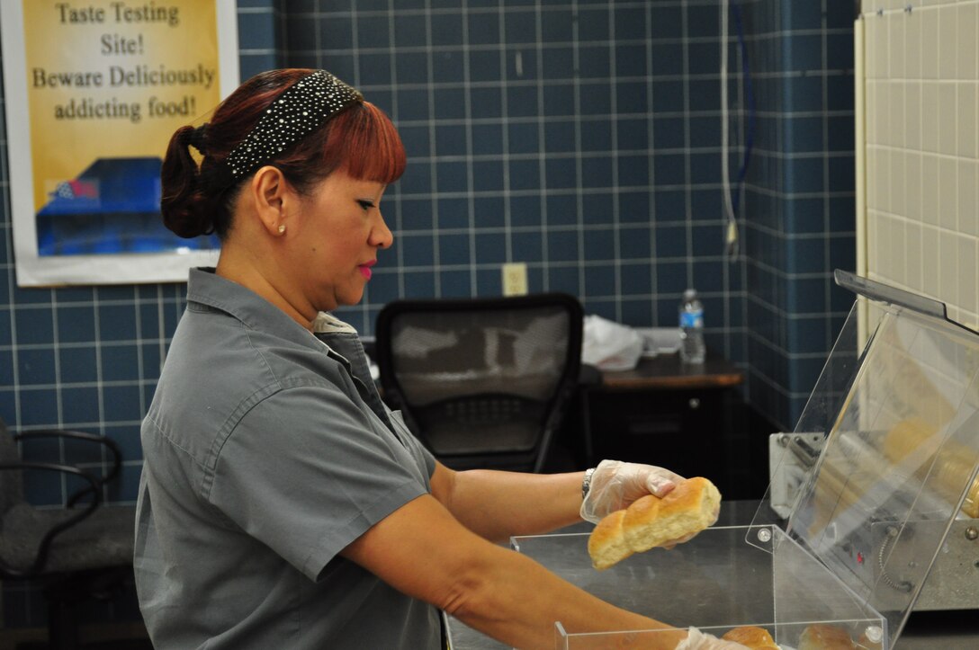 Elise Richards, DFAC contractor shift leader, places bread rolls in case for consumption during the lunch shift at the Berg-Liles Dining Facility Feb 27. The dining facility is open for Airmen seven days a week for breakfast, lunch and dinner. (U.S. Air Force photo by Airman 1st Class Solomon Cook)