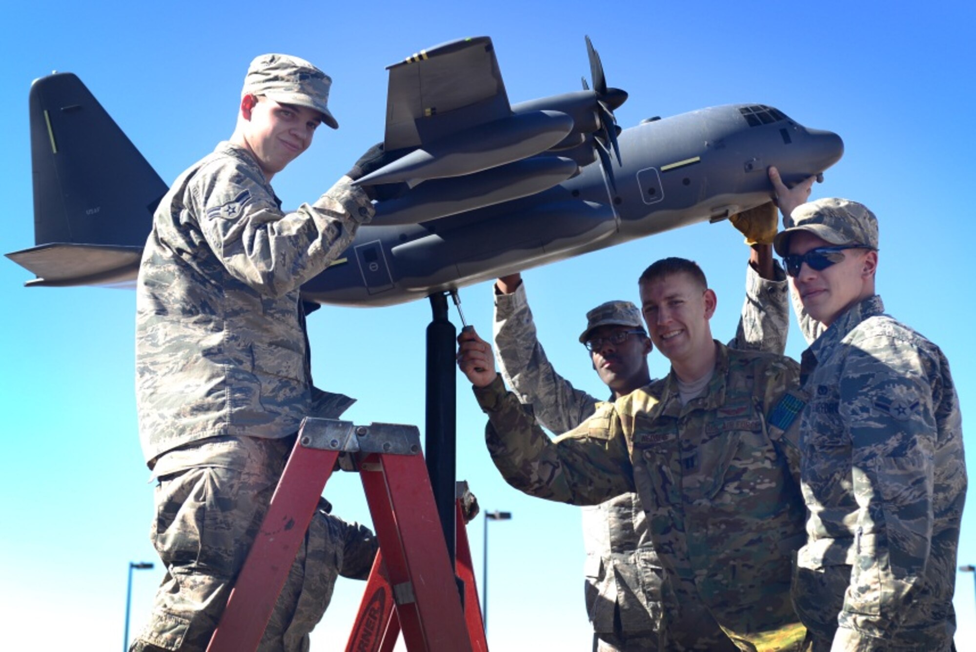 U.S. Air Force Airman 1st Class Marc Remsen, Senior Airman Bryce Williams and Airman John McClain, 27th Special Operations Civil Engineer Squadron members, pose with Capt. Anders Hedberg, 522nd Special Operations Squadron pilot, after mounting a miniature MC-130J static display Feb. 24, 2014 at Cannon Air Force Base, N.M. The display, which previously stood outside of the Pecos Trail Dining Facility, was relocated to the front of the new 522 SOS building. (U.S. Air Force photo/Airman 1st Class Shelby Kay-Fantozzi) 