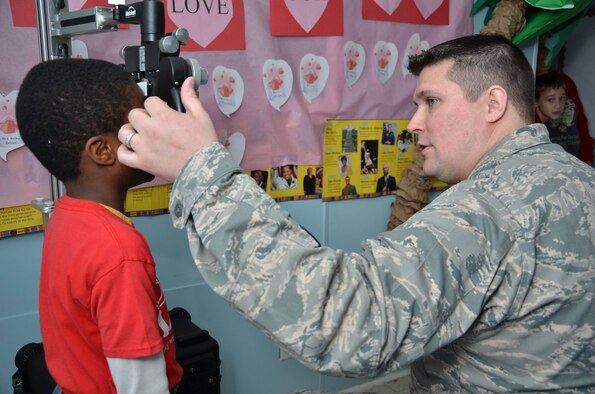 A picture of U.S. Air Force Maj. Jason Winterbottom examining a child's eyes.