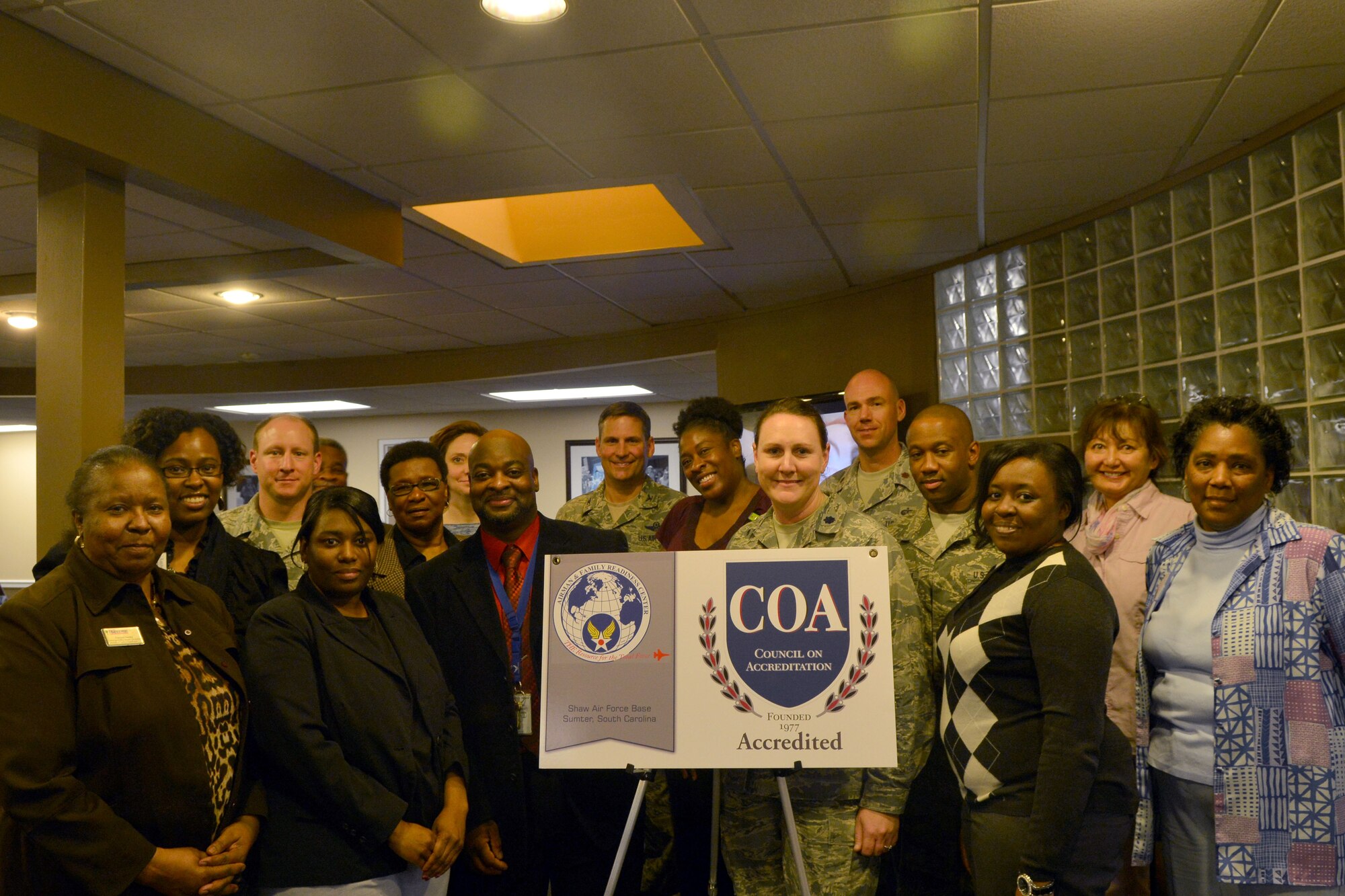 U.S. Air Force Col. Clay Hall, 20th Fighter Wing commander (center) and Lt. Col. Tara White 20th Force Support Squadron commander (front left) pose for a group photo with the Airman and Family readiness Center staff at Shaw Air Force Base, S.C., Feb. 26, 2014. The Airman and Family Readiness Center unveiled their achieved national accreditation and plaque. (U.S. Air Force photo by Senior Airman Ashley L. Gardner/Released)