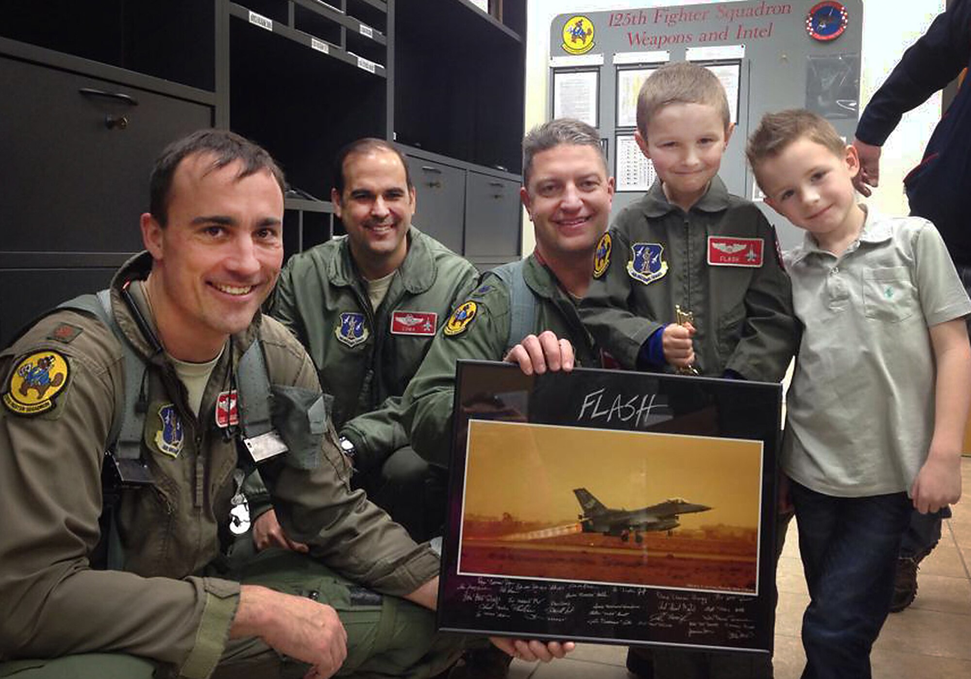 While being a "Pilot for a Day", 19 February 2014,  at the 138th Fighter Wing, Oklahoma Air National Guard, Tulsa, Okla., Zip "Flash" Gordon receives a framed photo of a Tulsa F-16 taking off.   Major Eric Jauquet, Lieutenant Colonel Ryan Jones, Lieutenant Colonel Matthew Bertelli, and Zip's good friend Ethan Sikes were on hand for the presentation.  (U.S. National Guard photo by Senior Airman Jasmine Stone/Released)