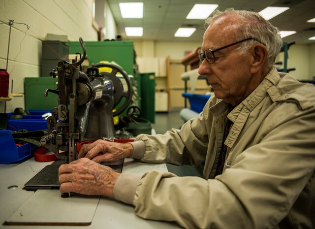 Bobby Pierce, 437th Aircrew Flight Equipment fabrication shop, uses a sewing machine designed to work with thick materials, to stich a strap, used by paratroopers, that locks into the harness line of an aircraft Feb. 20, 2014, at Joint Base Charleston – Air Base, S.C. Pierce has worked in the fabrication shop for more than 30 years. (U.S. Air Force photo/ Senior Airman Dennis Sloan)
